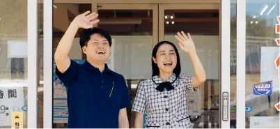 男性指導員と女性指導員が手を振る様子