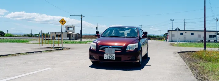 ワインレッド色の教習車に乗って、構内教習を受けている様子