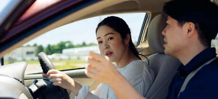 教習車の中から女性教習生が左方向を確認している様子