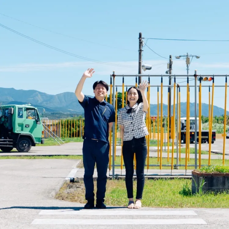 教習所コースから手を振っている男性指導員と女性指導員