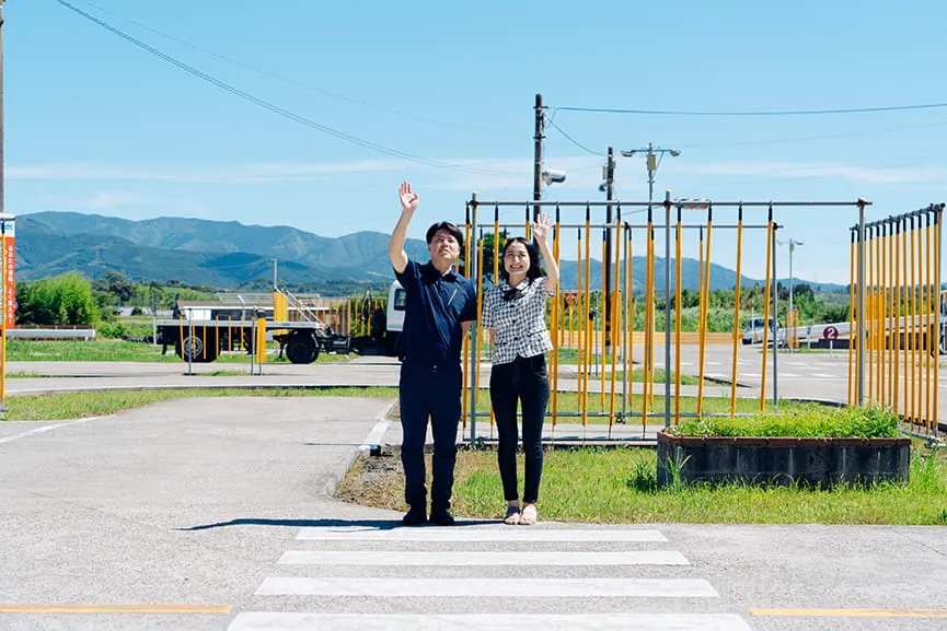 教習所のコースからから手を振る男性指導員と女性指導員の様子