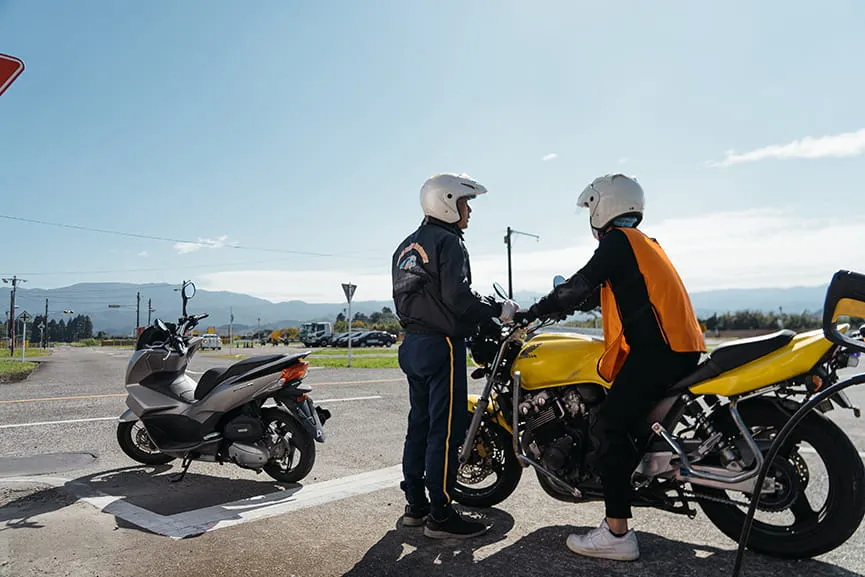 バイクにまたがっている教習生に横で指導をしている男性指導員の様子