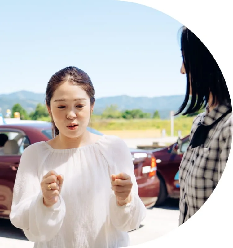 教習車の前で指導を女性指導員から受けている女性教習生の様子