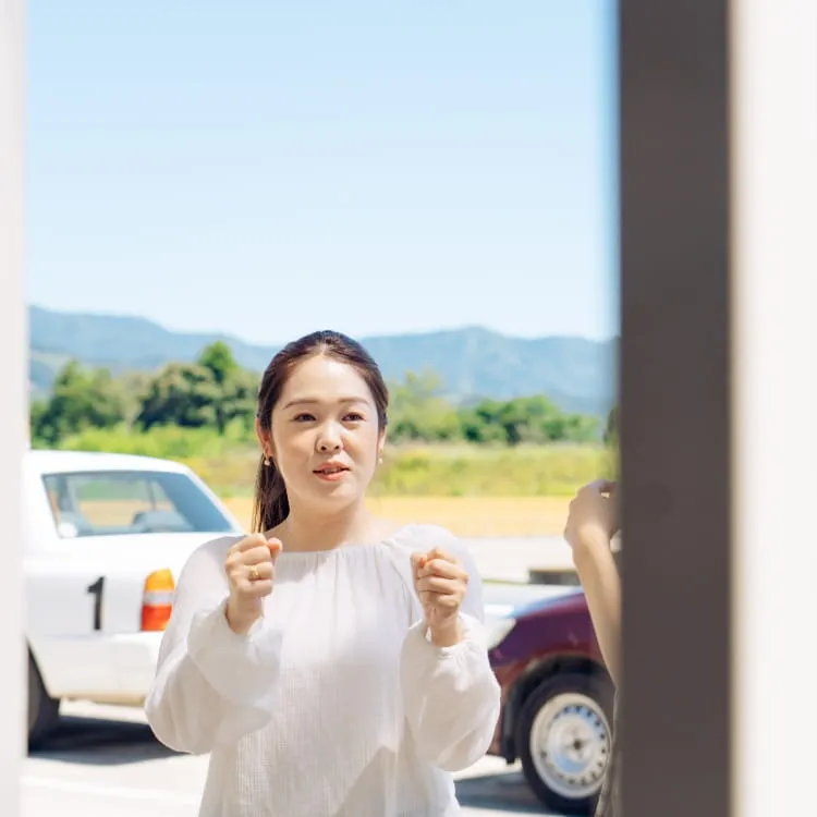 教習所内でハンドルを握っているポーズしている女性教習生の様子