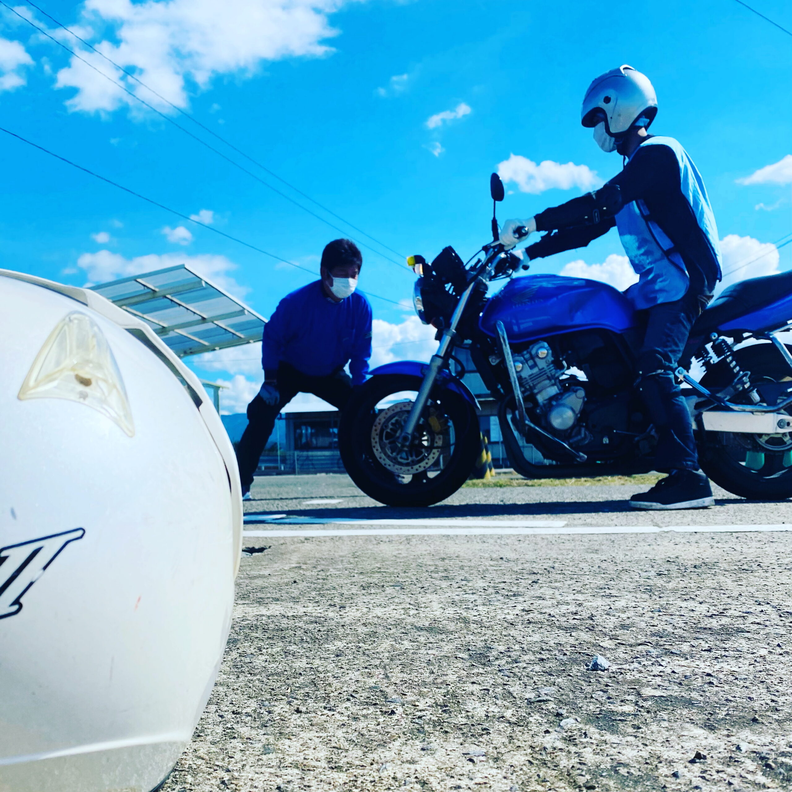 都城ドライビングスクールの教習コースでバイク教習を受けている教習生と指導している指導員様子