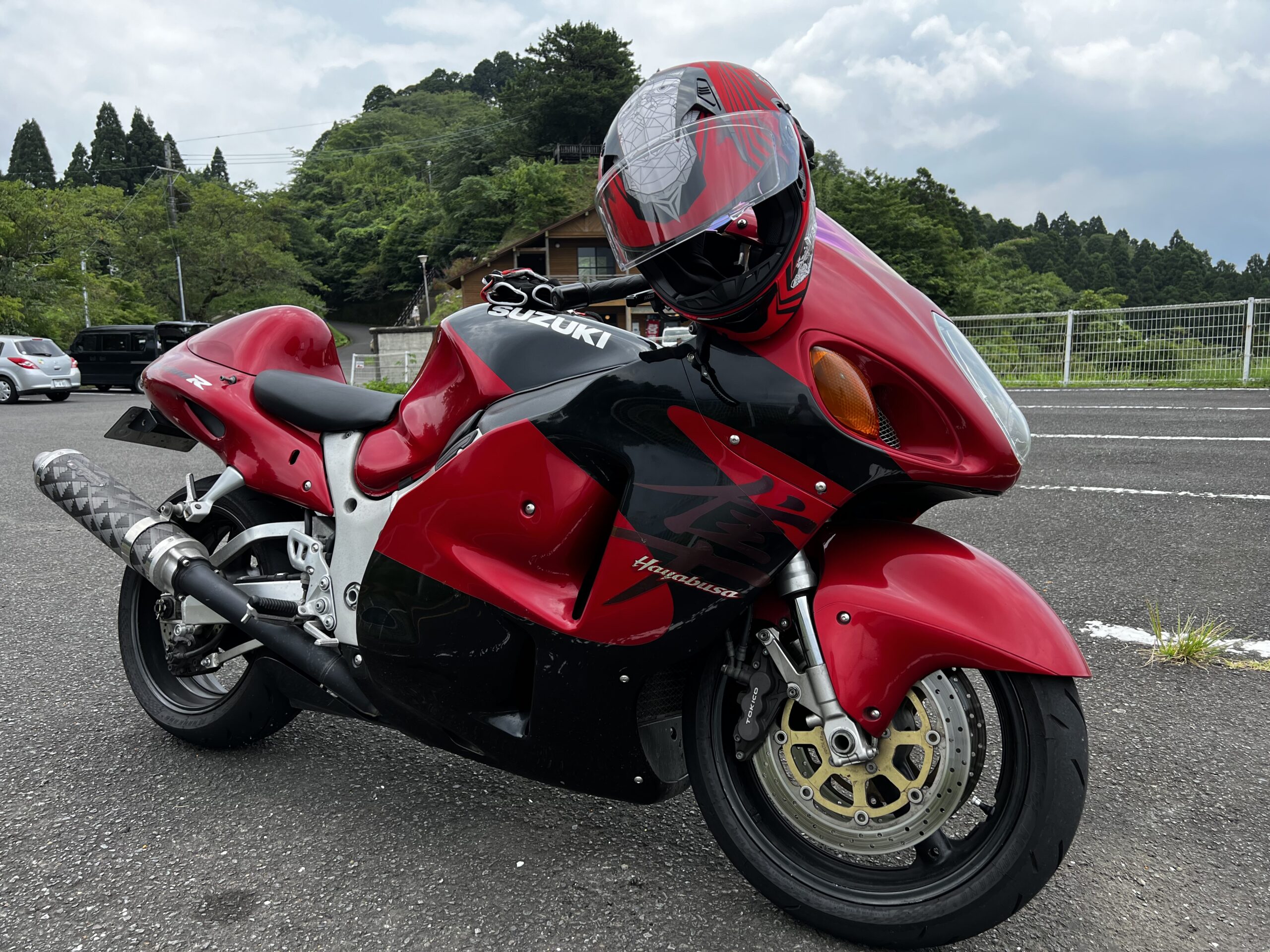 山間の駐車場に止めているSUZUKIの赤いバイク